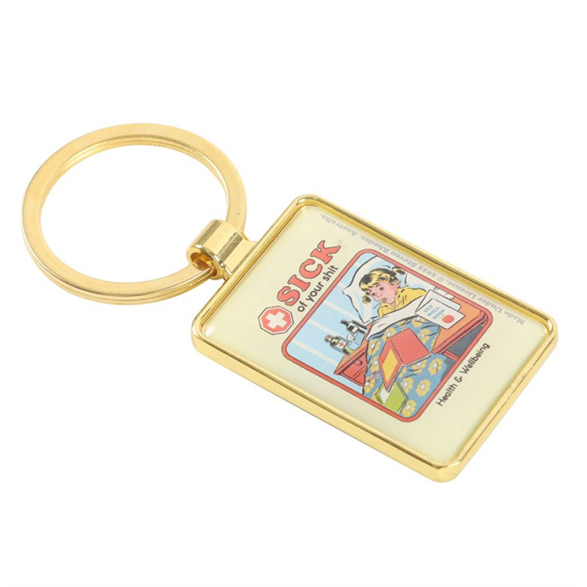 Steven Rhodes enamel keyrings depicting a young girl with bunches lying in bed with a thermometer in her mouth. On the bedside table are bottles of medicine and get well soon cards, the text reads 'Sick of your Shit'.