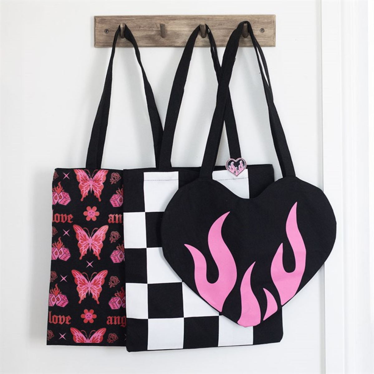Black heart-shaped tote bag with contrasting pink flame detailing. Displayed with other items from the same range.