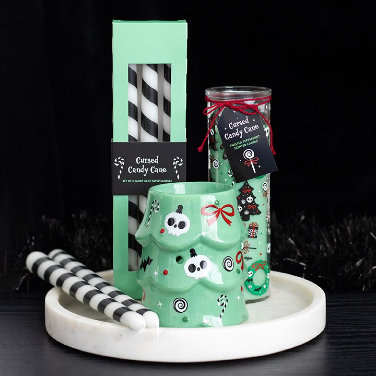 Ceramic wax melter and oil burner shaped like a traditional christmas tree, decorated with halloween-themed decorations. Presented alongside other items from the same range.