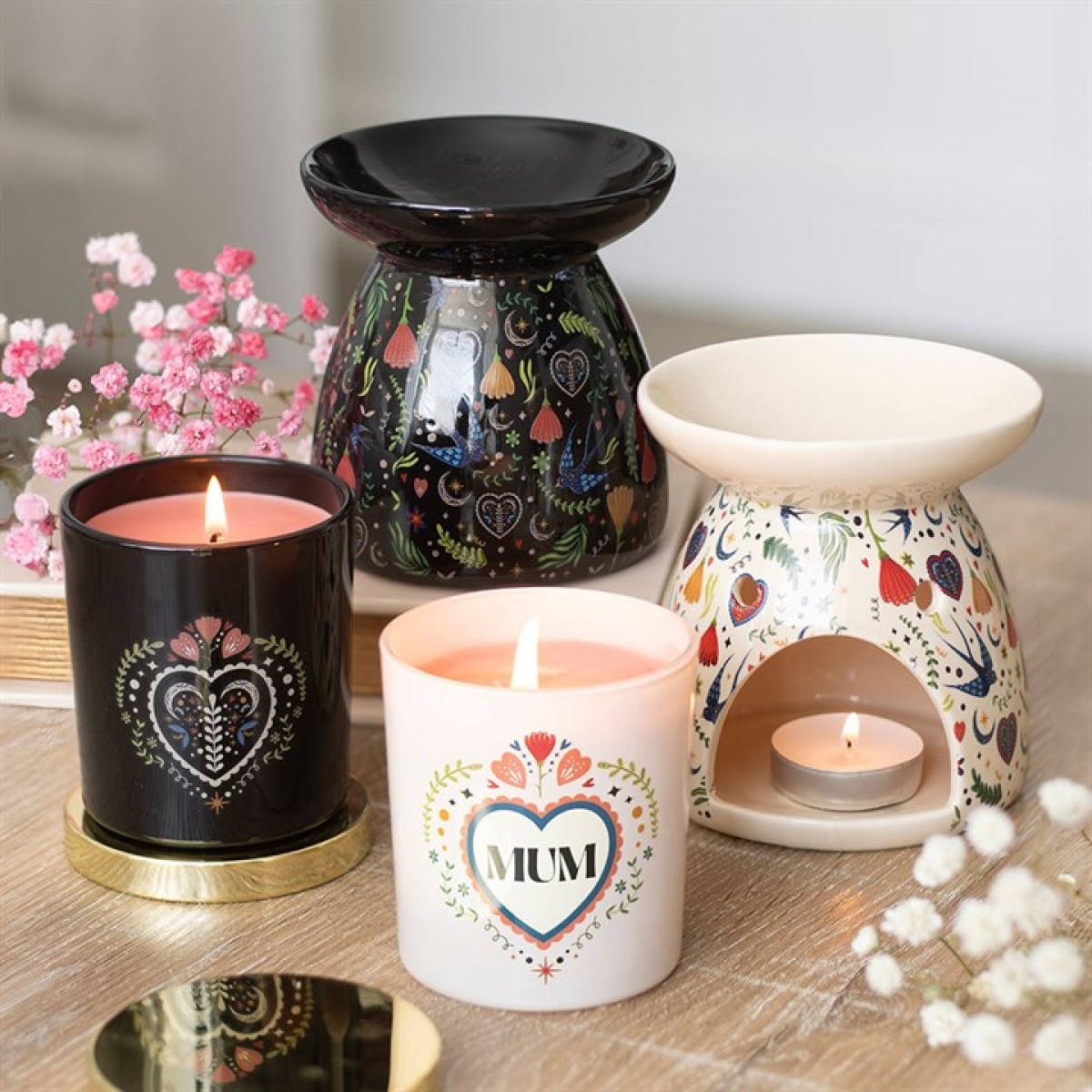 Black gloss ceramic wax melter and oil burner with folksy fauna and flora print. Presented alongside other items from the same range.