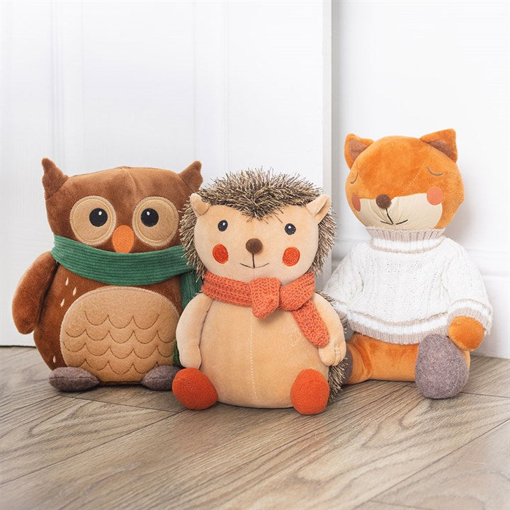 Woodland-themed weighted doorstop, shaped like a hedgehog with knitted orange scarf. Presented alongside a fox and an owl shaped doorstop from the same range.
