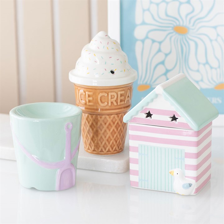 Pastel coloured beach bucket shaped wax melter and oil burner. Presented alongside other items from the same range.