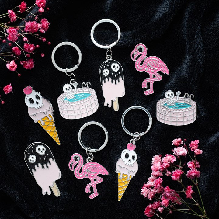 A flamigo-gothic style keyring featuring a skeleton flamingo. Presented alongside other items from the same range.