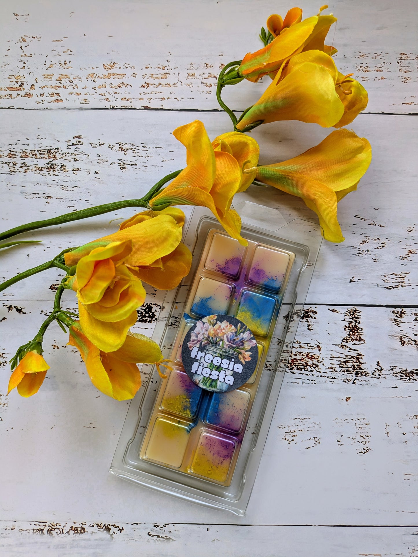 Freesia Fiesta coconut wax melt. Light yellow snap bar with purple, blue and yellow shimmer accents.