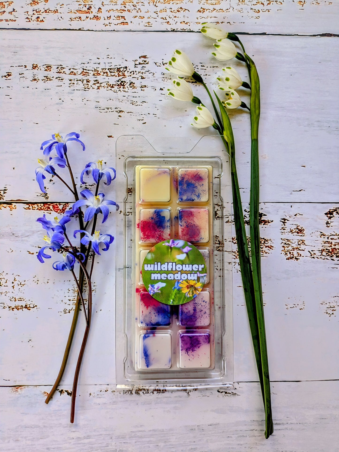 Wildflower Meadow coconut wax melt. Cream snap bar with blue, pink and purple shimmer accents.