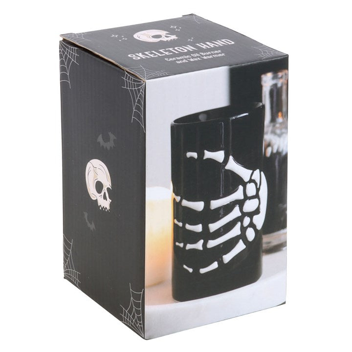 Ceramic wax melter and oil burner, decorated with a skeleton hand. Presented in a themed box.