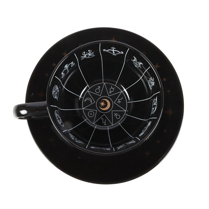 Black ceramic teacup and saucer set, designed with astrology wheel illustrations and sold with a tea leaf reading guide. Inside detailing view.