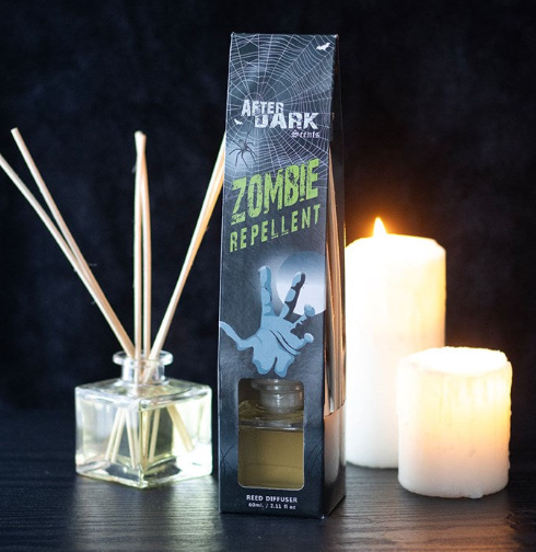 squat square glass bottle with oil fragrance and reeds. Next to a box of Zombie Repellent reed diffuser. 