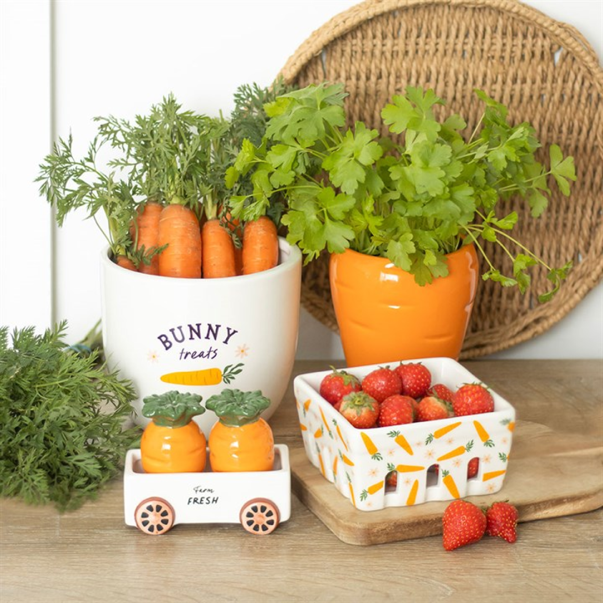 Ceramic berry basket with carrot and white floral motif. Presented alongside other items from the range. 