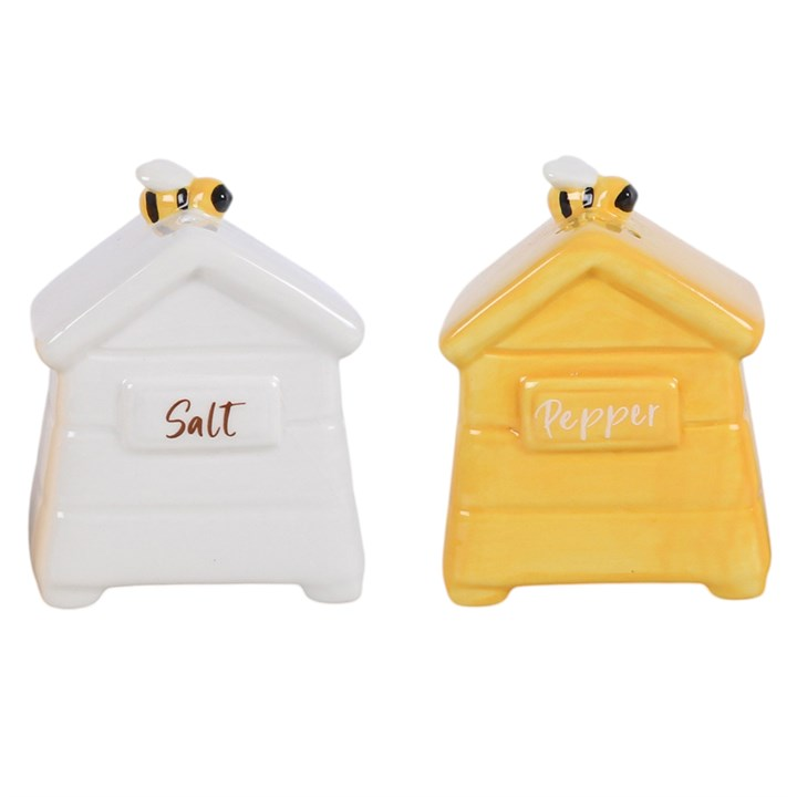 A set of white and yellow ceramic salt and pepper shakers, shaped like traditional beehives with a bee sitting on top. 