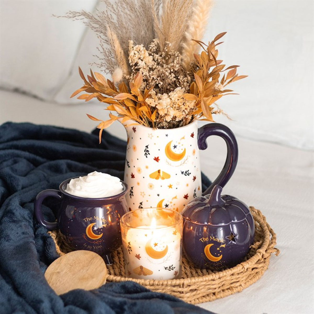 White ceramic flower jug with harvest moon motifs including crescent moons, moths and floral accents. Presented alongside other items from the same range. 