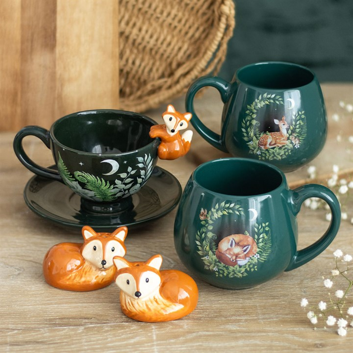 Green rounded ceramic mug with a charming sleeping fox nestled in the forest design. Presented alongside other items from the same range.