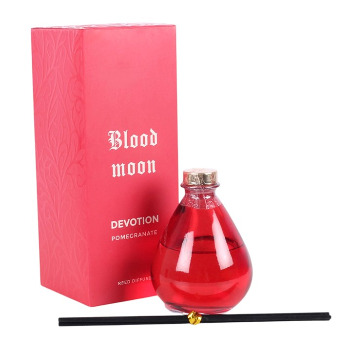 Blood Moon reed diffuser, including deep pink teardrop-shaped glass bottle and reeds. 
