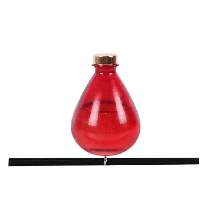 Blood Moon reed diffuser, including deep pink teardrop-shaped glass bottle and reeds. 
