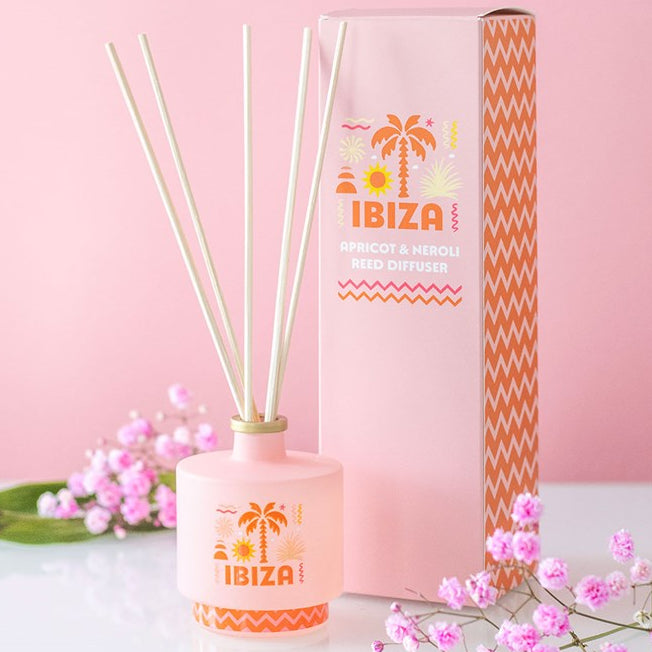 Ibiza reed diffuser, a soft pink bottle with orange palm tree and coastline inspired design. 
