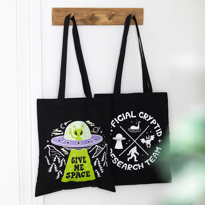 Black tote bag with adorable extraterrestrial and ufo design. Displayed alongside other items from the same range. 