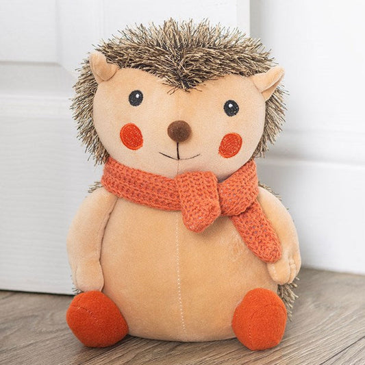 Woodland-themed weighted doorstop, shaped like a hedgehog with knitted orange scarf. 