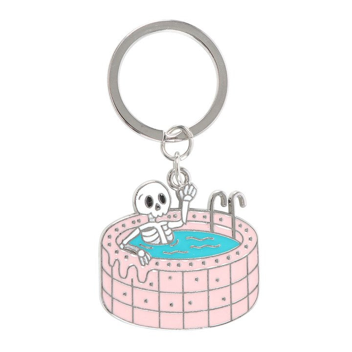 Dead Cool enamel keyring shaped like a skeleton chilling in a pink swimming pool. 