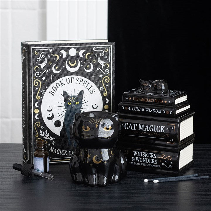 Wax melter and oil burner shaped like a stack of gothic books with a sleeping-cat detailed lid. Presented alongside other items from the same range.