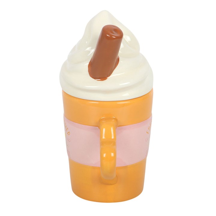 Fresh brewed pumpkin spiced latte mug with whipped cream shaped lid and cinnamon stick embellishment. Side view.