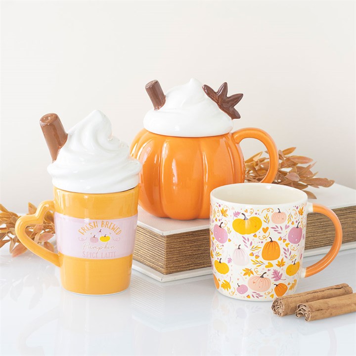 Pumpkin shaped mug with a whipped cream shaped lid, finished with cinnamon embellishment. Presented alongside other items from the same range.