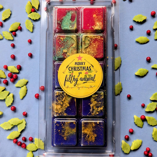 Merry Christmas Ya Filthy Animal coconut wax melt. Red and blue snap bar with gold and green shimmer accents.