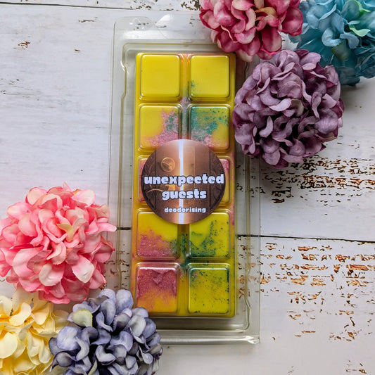 Unexpected Guest odour eliminating coconut wax melt. Yellow snap bar with purple and green shimmer accents. 