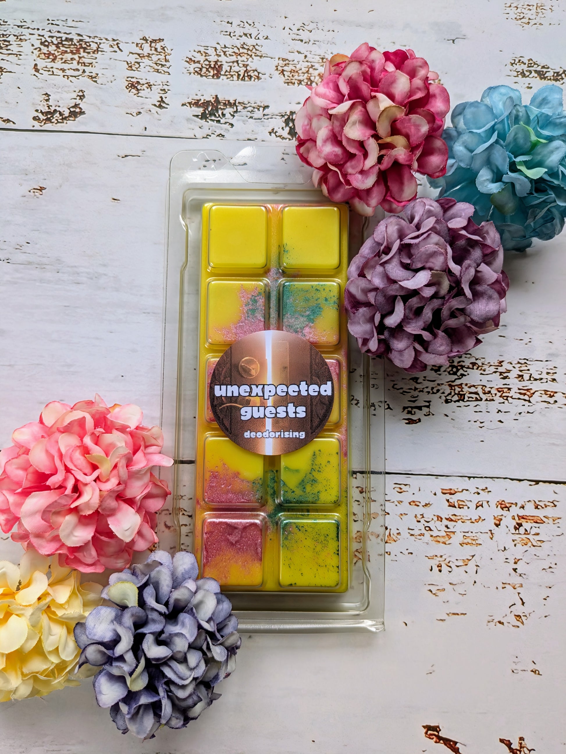 Unexpected Guest odour eliminating coconut wax melt. Yellow snap bar with purple and green shimmer accents. 