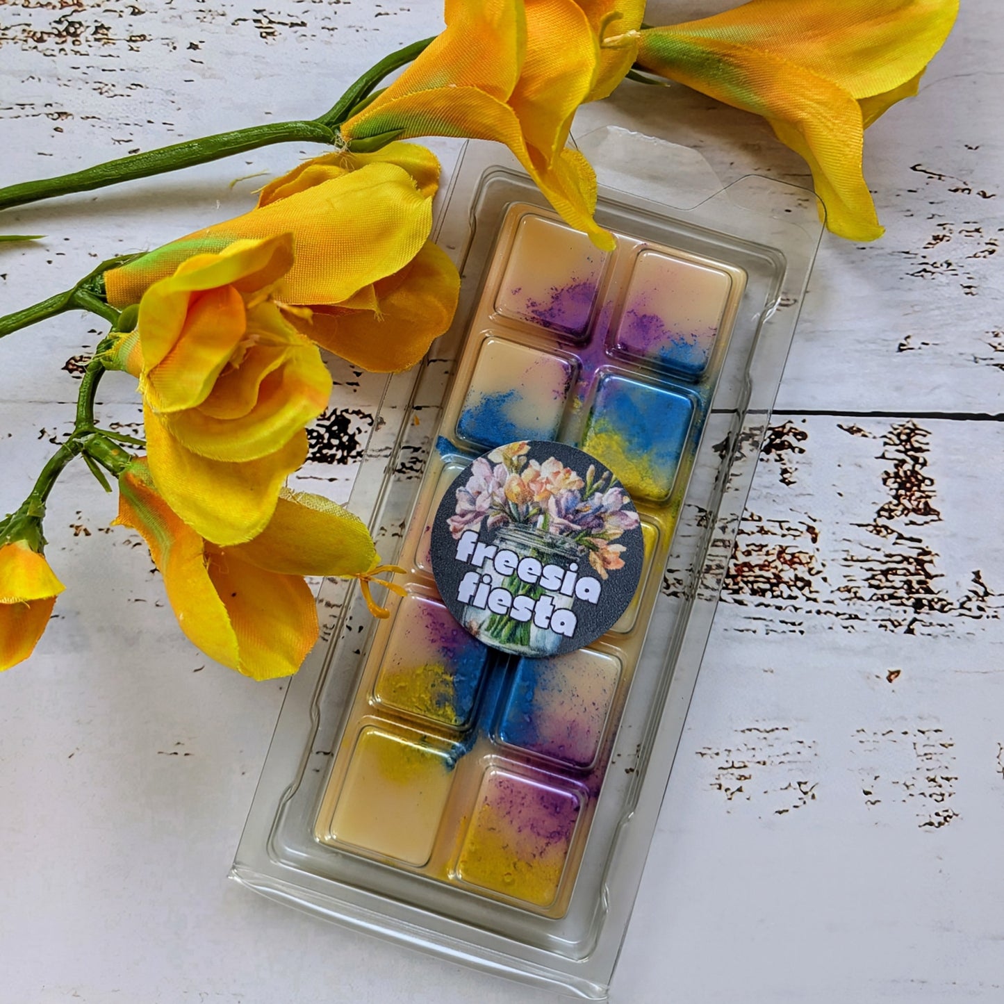 Freesia Fiesta coconut wax melt. Light yellow snap bar with purple, blue and yellow shimmer accents.