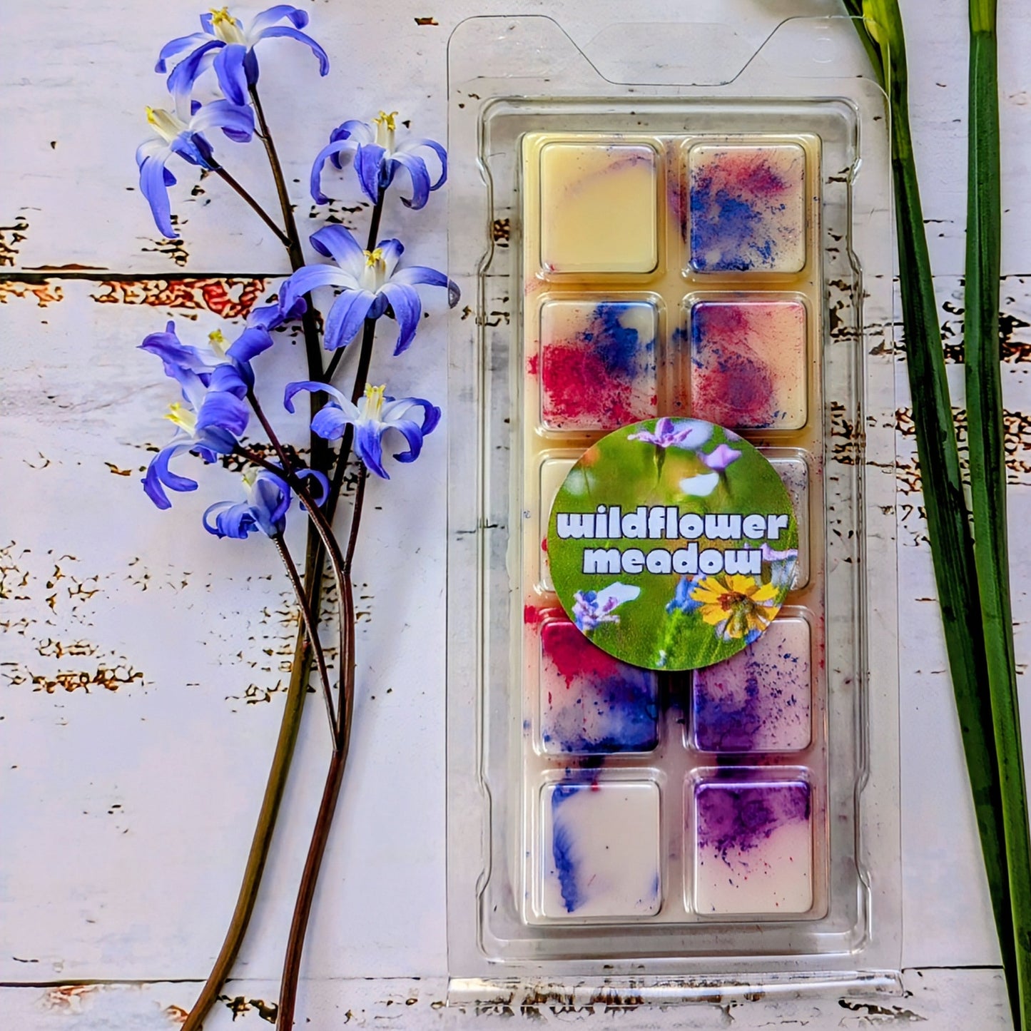 Wildflower Meadow coconut wax melt. Cream snap bar with blue, pink and purple shimmer accents.