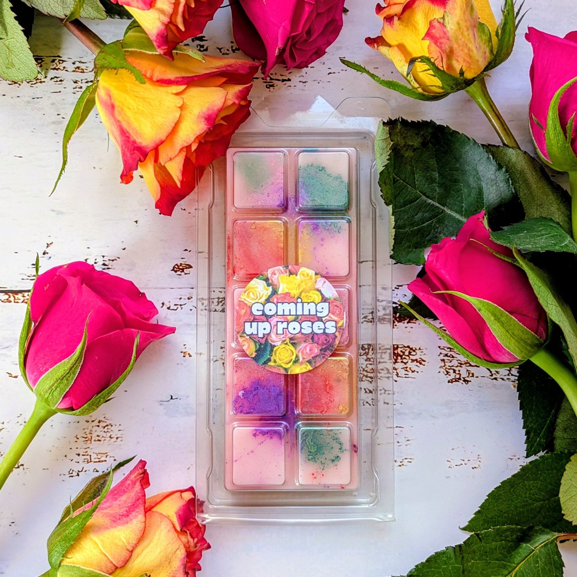 Coming Up Roses coconut wax melt. Light pink snap bar with green, purple, pink and yellow shimmer accents. 