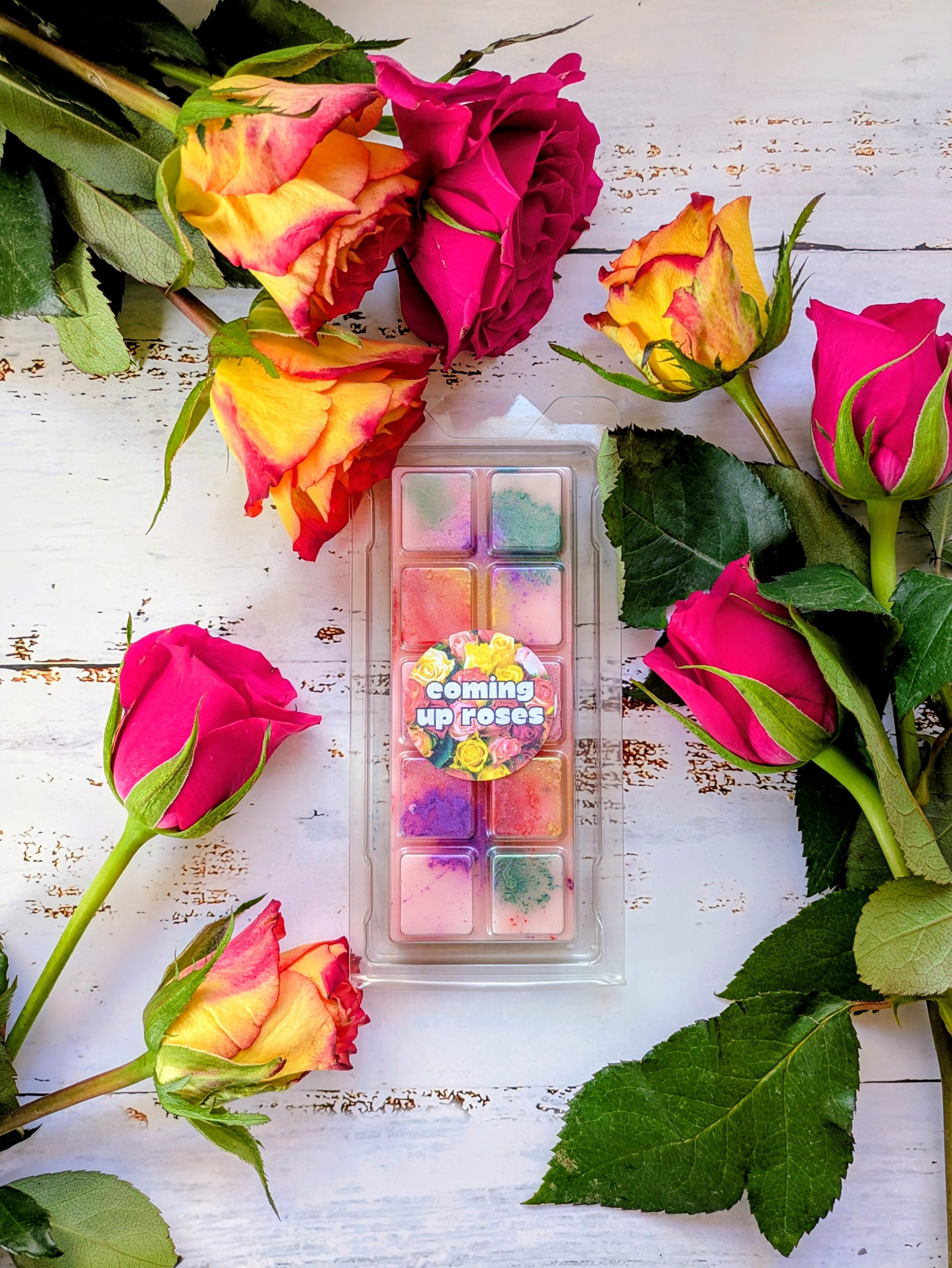 Coming Up Roses coconut wax melt. Light pink snap bar with green, purple, pink and yellow shimmer accents. 