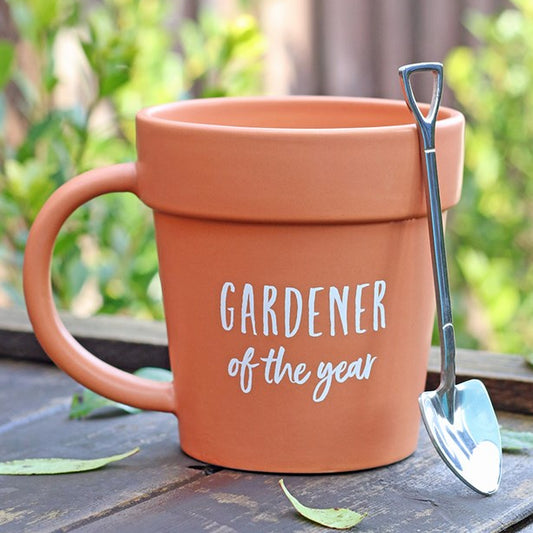 Ceramic terracotta-coloured mug which looks like a plant pot. Includes a shovel shaped spoon and 'Gardener of the Year' text.