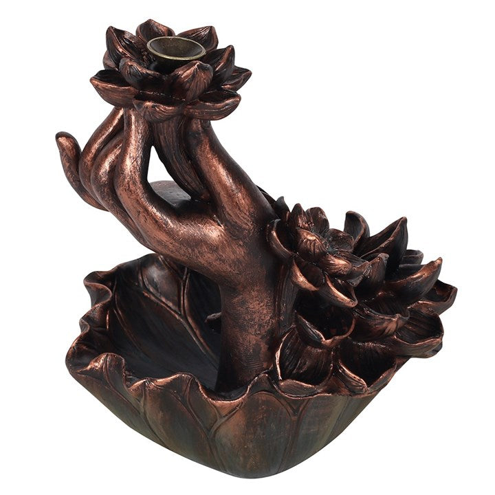 Intricate hand and flowers backflow incense burner in a dark copper effect finish.