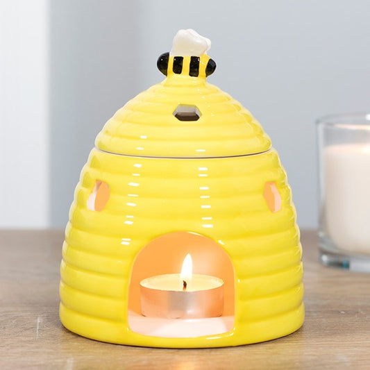 Yellow ceramic beehive wax melter and oil burner. Honeycomb cutouts with a bee-topped lid. 
