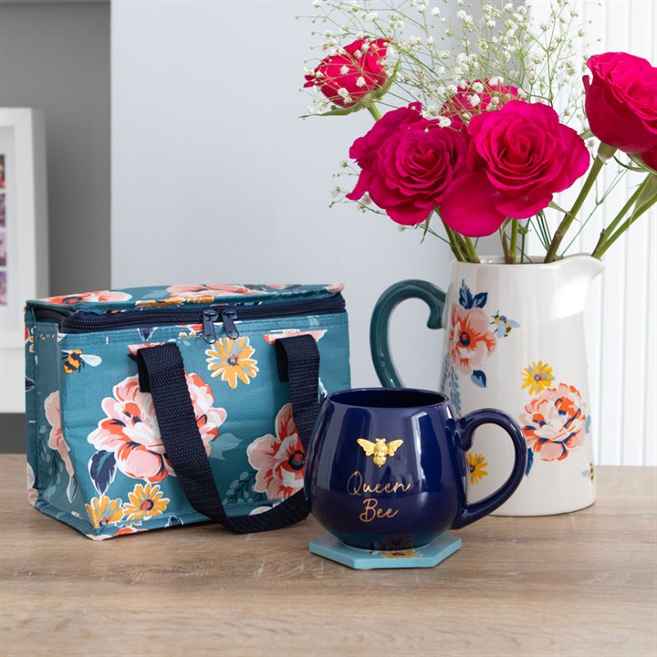 White pitcher with floral and bee illustrations and navy blue handle. Presented alongside other items from the same range.