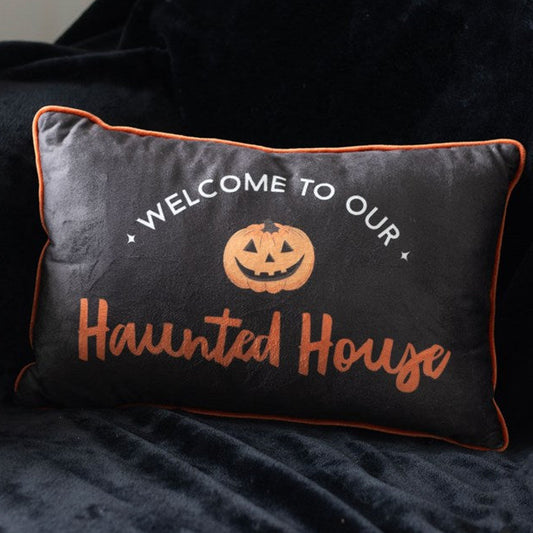 Rectangular Halloween throw cushion. Black background with an orange trim, Welcome to our Haunted House text and jack o' lantern motif.