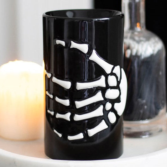 Ceramic wax melter and oil burner, decorated with a skeleton hand.