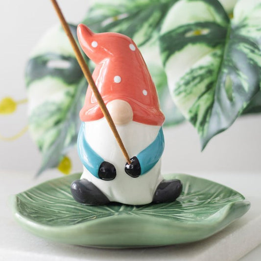 Gonk shaped incense stick holder, resting on a garden leaf.