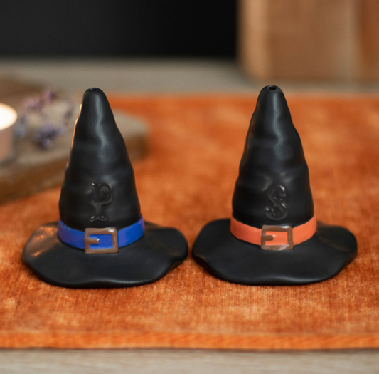 Two black witches hat-shaped salt and pepper shakers with orange and blue belts. 