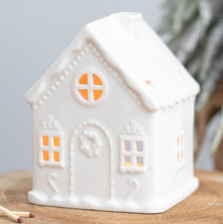 White ceramic tea light holder shaped like a traditional gingerbread house. 