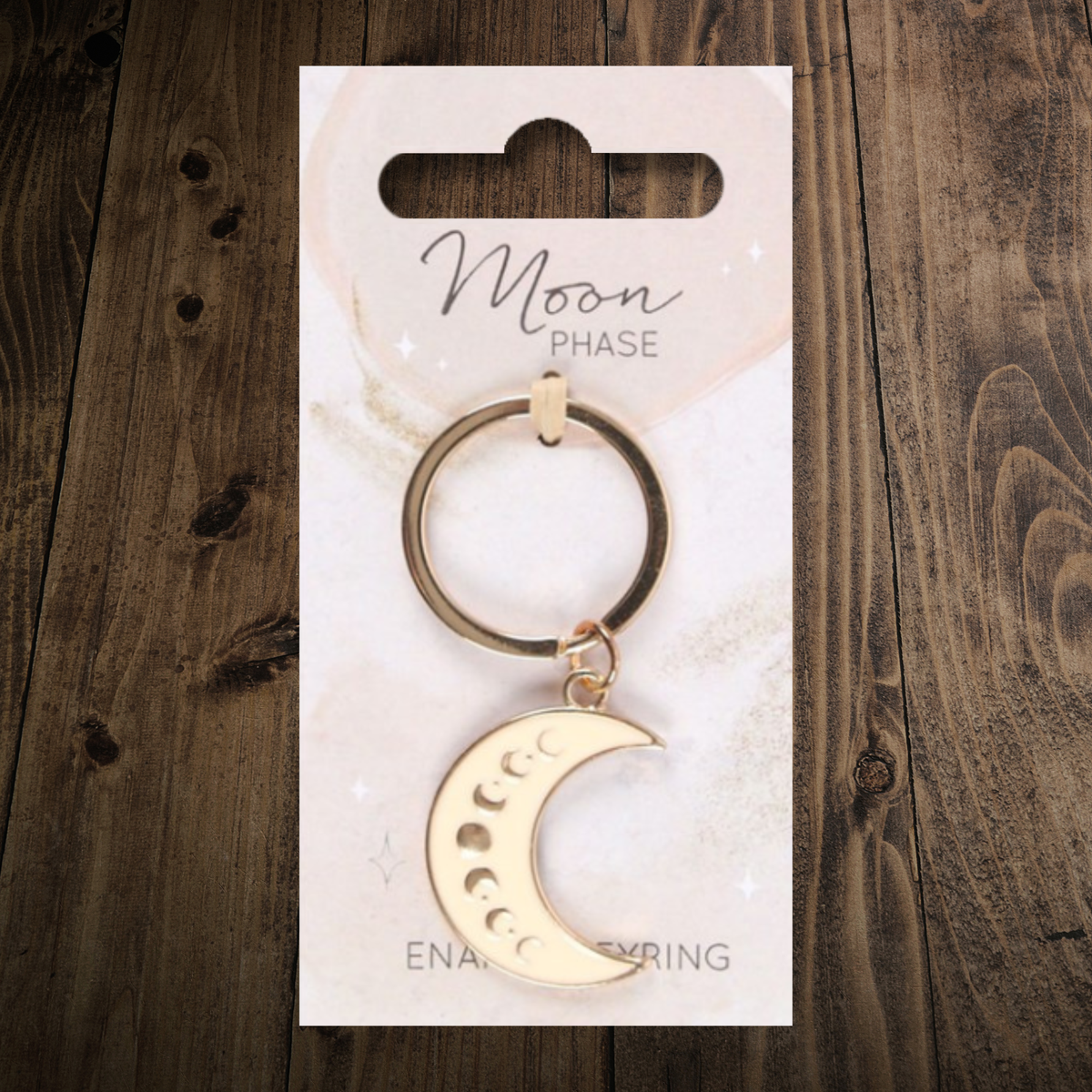 White, crescent moon shaped enamel keyring with phases of the moon detailing. Presented on a matching backing card. 