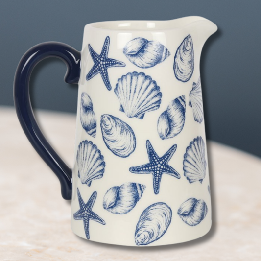 White ceramic flower jug with blue seashell and starfish motif.