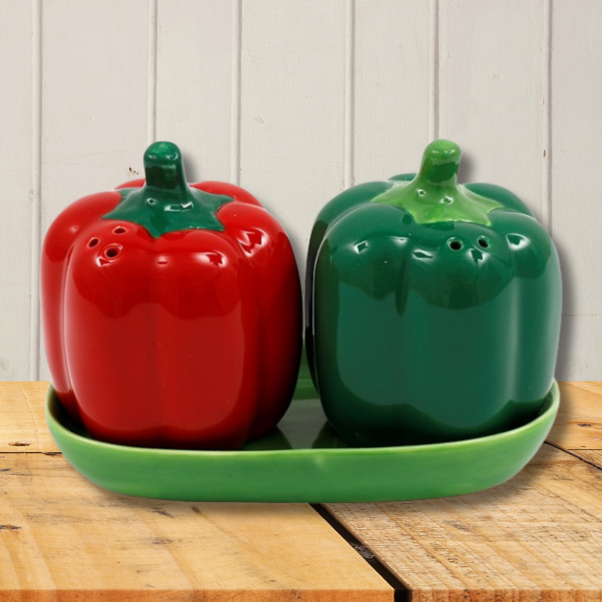 Pair of red and green pepper shaped salt and pepper shakers, presented on a green tray.