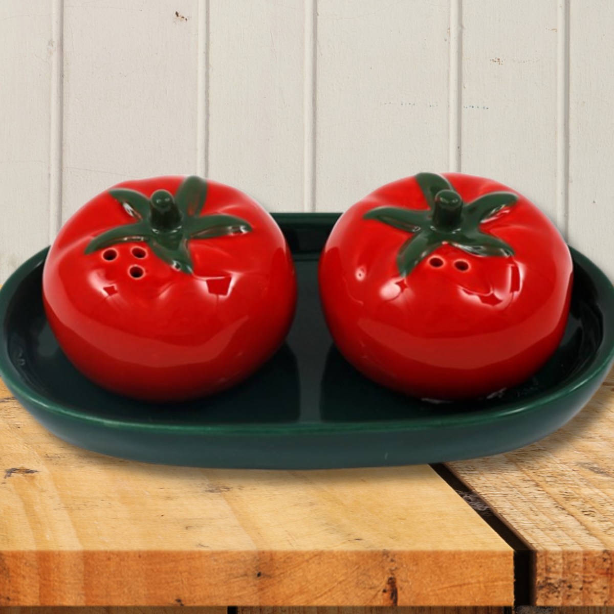 Pair of tomato shaped salt and pepper shakers, presented in a green tray. 