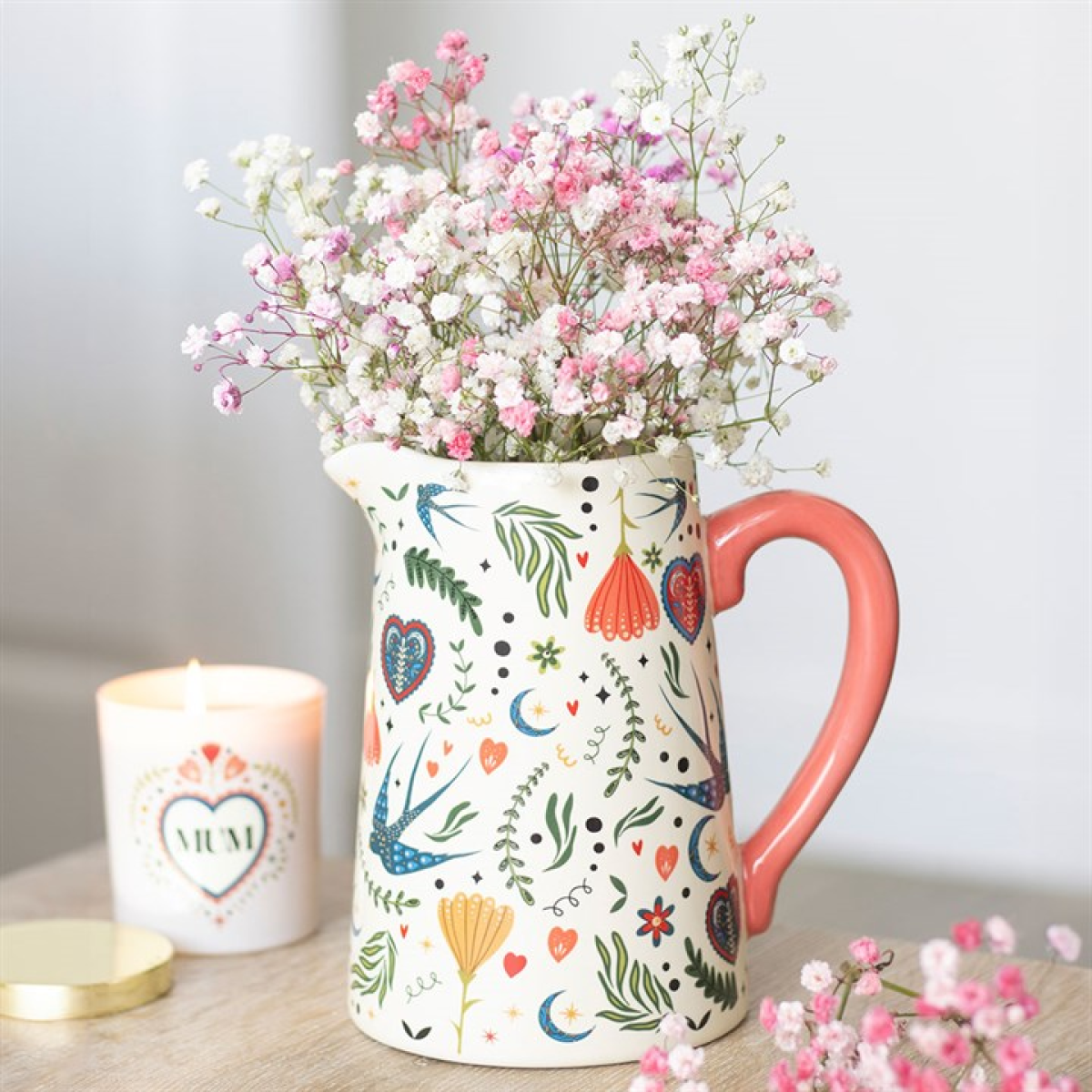 Bohemian flower jug with folk-style motif and pink handle.