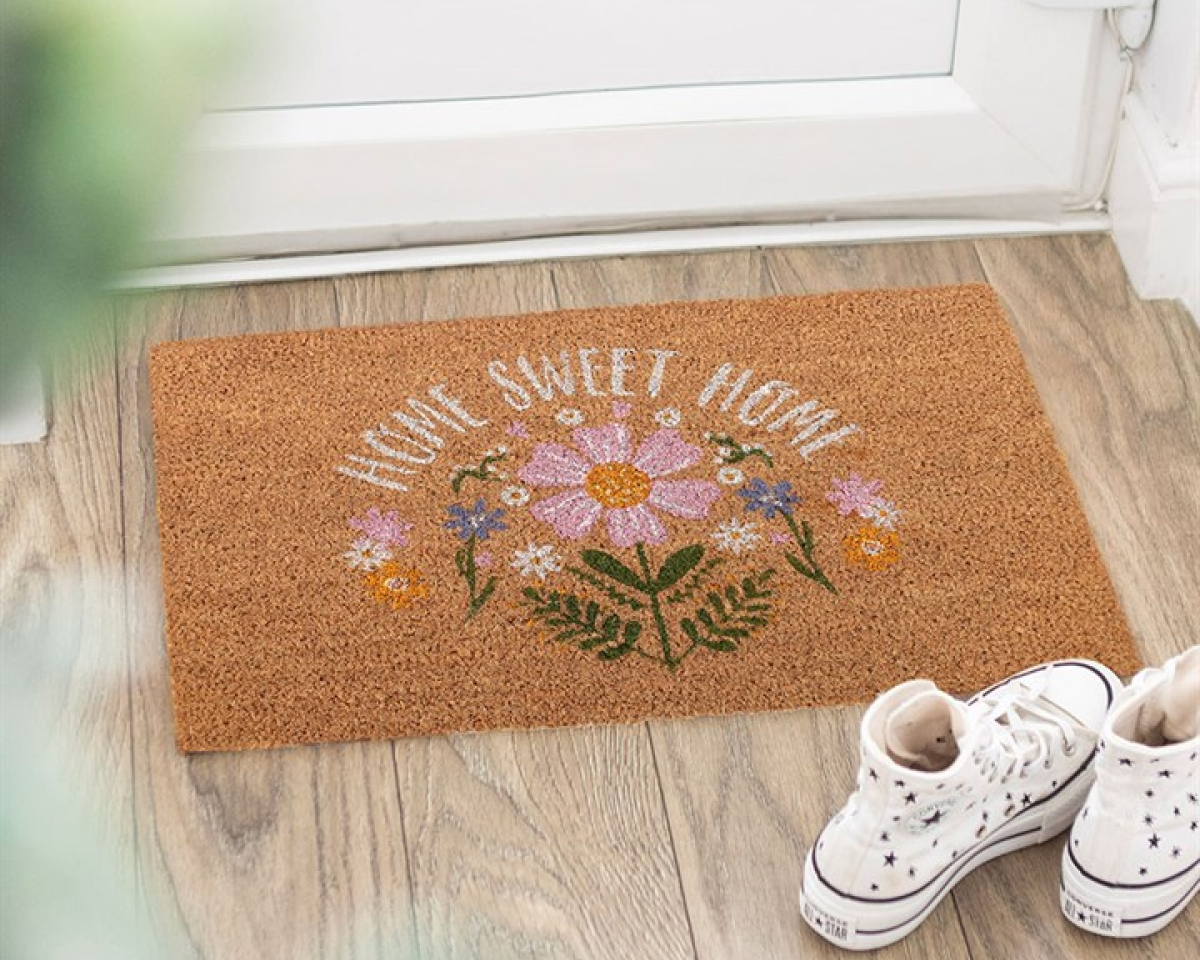 Decorative doormat with 'Home Sweet Home' and daisy design on a natural fibres background.