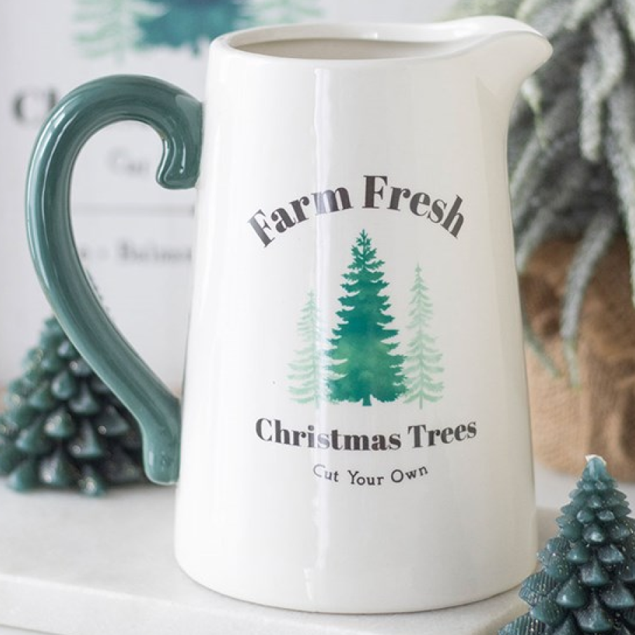 White ceramic pitcher style flower jug, with festive Farm Fresh Christmas Trees (Cut Your Own) design and coordinating green handle. 