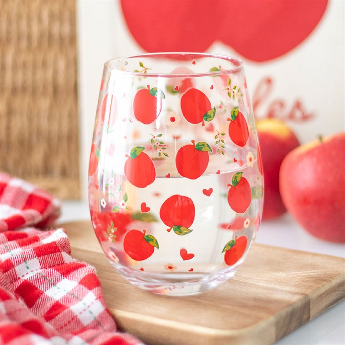Clear rounded water glass covered in a red apple motif.