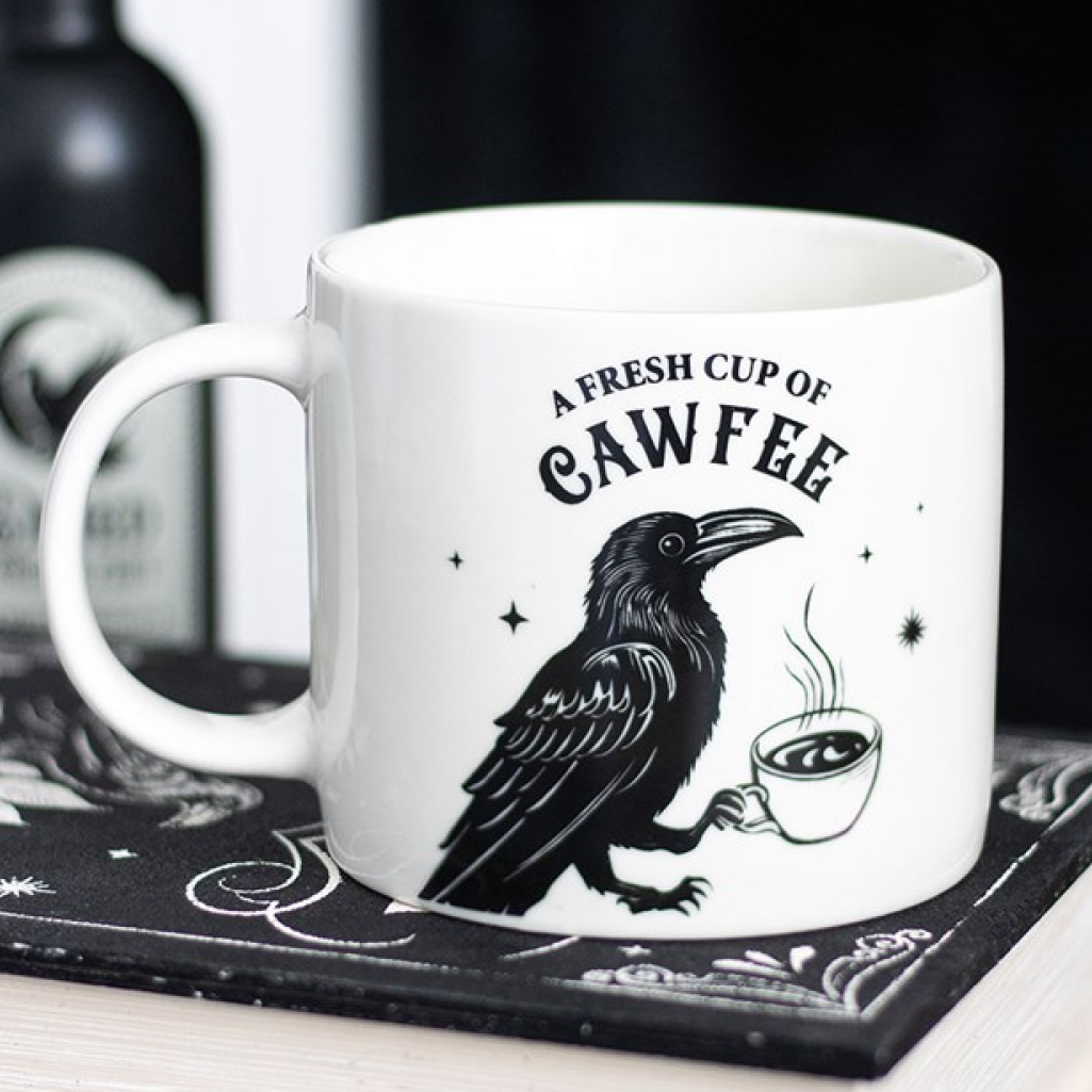 White ceramic mug with a cheeky gothic design - a raven holding a steaming cup of coffee - with 'A Fresh Cup of Cawfee' text.